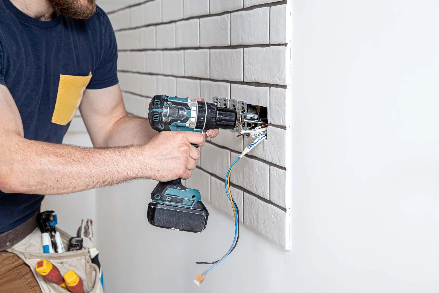 Technician fitting a wall outlet with a cordless drill